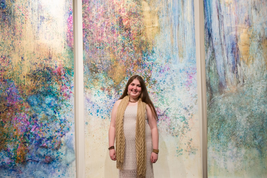 Adelia Roberts '15 in front of her paintings at her BFA exhibition in the Samuel Dorsky Museum of Art