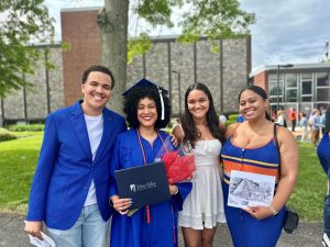 A new graduate happily poses with her diploma alongside her son and two daughters on Commencement Day. 